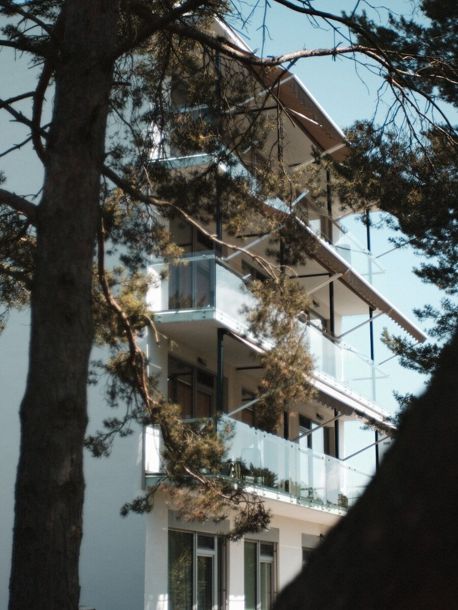 a tall white building sitting next to a tree